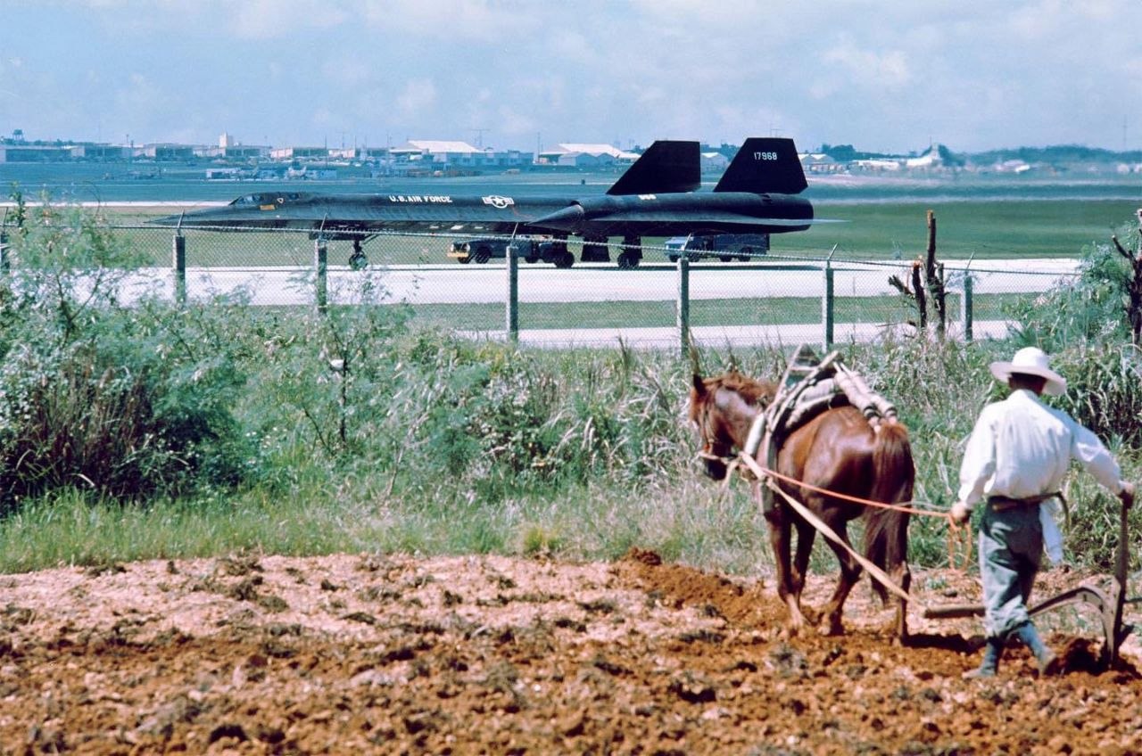 Horse plowing field with supersonic plane SR71 in background